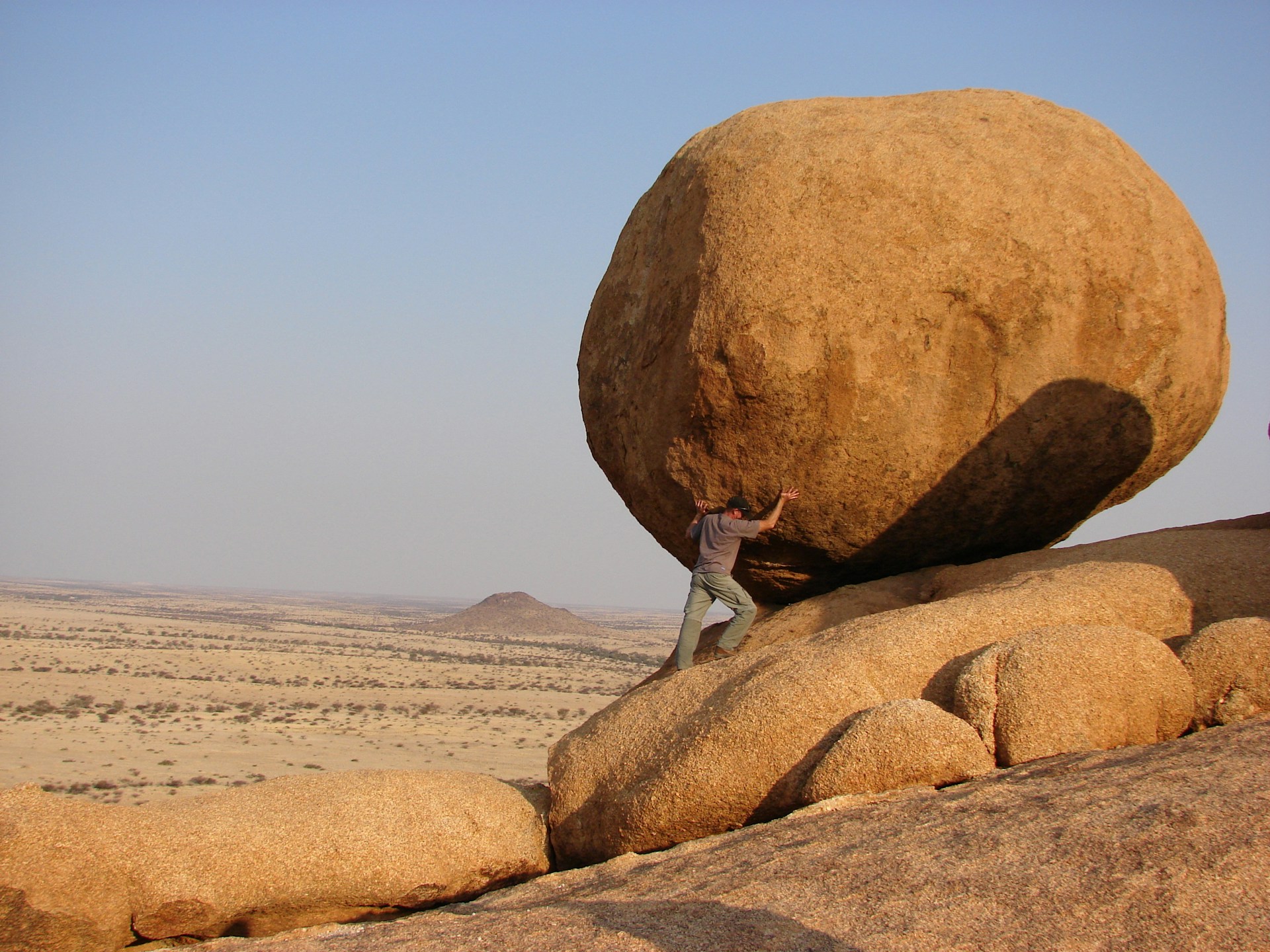 Man pushing a boulder uphill